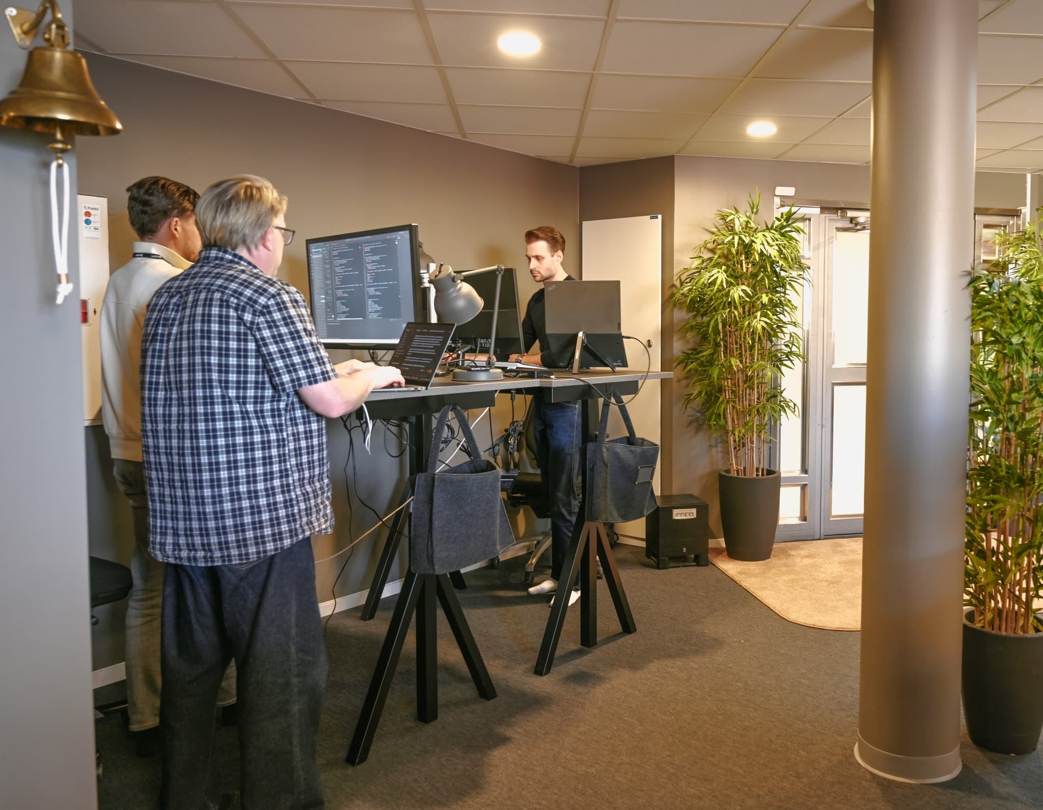 Tre kollegor som samarbetar vid ett ståbord med extern skärm på River Street Lab i Linköping